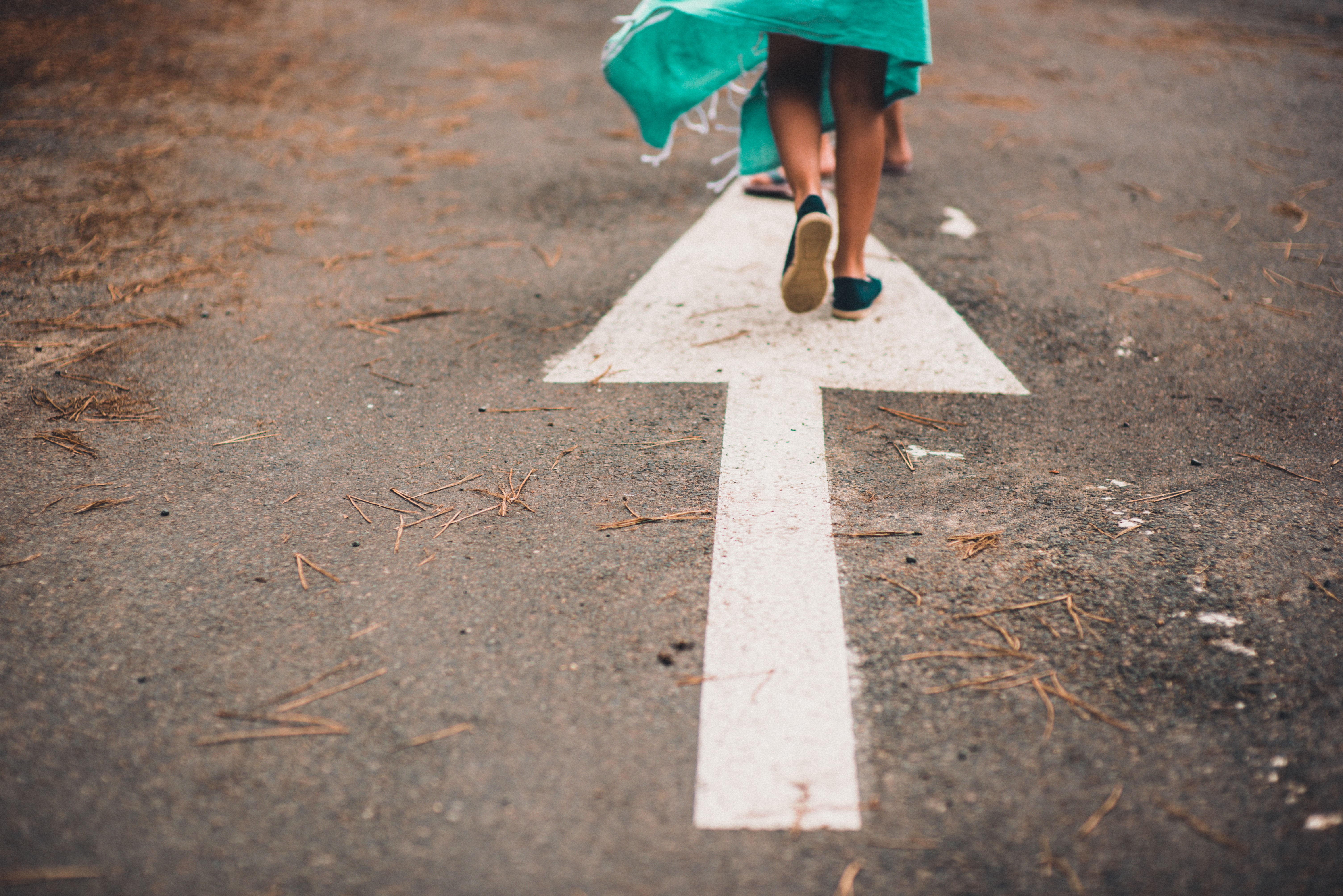 Picture of a white arrow pointing forward painted on pavement